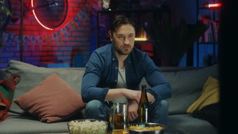 handsome of the caucasian young man watching tv at night and drinking beer, sport fan watching a game.