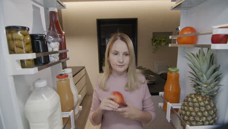 tarde en la noche, una mujer mira en el refrigerador y come dulces. bocadillos nocturnos y trastornos alimentarios