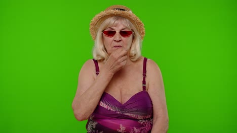 Elderly-woman-tourist-holding-finger-near-lips-for-silence-sign,-hush,-secret,-silence-on-chroma-key