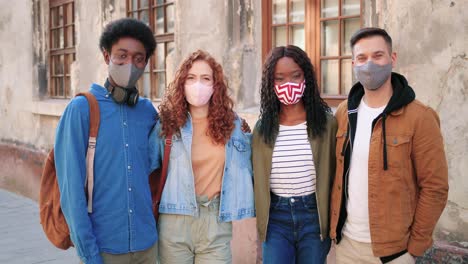 group of multiethnic friends wearing mask and looking at the camera in the street