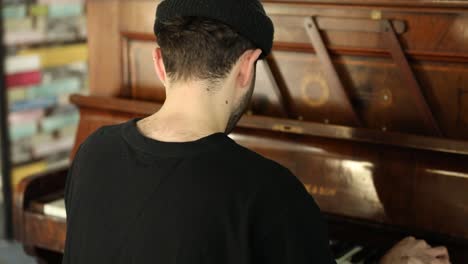 close up of man sitting on classic wooden piano and plays