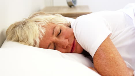 una mujer mayor sufriendo en su cama.