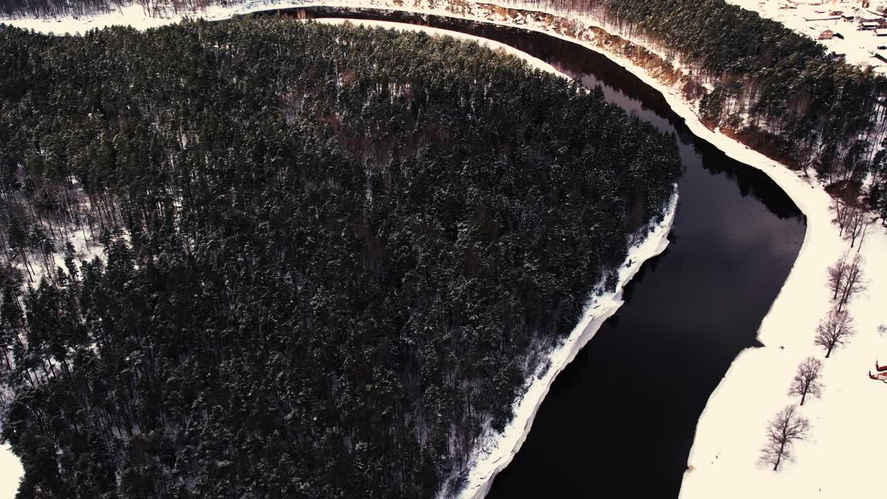 un río sinuoso cerca de un pequeño pueblo con un macizo forestal