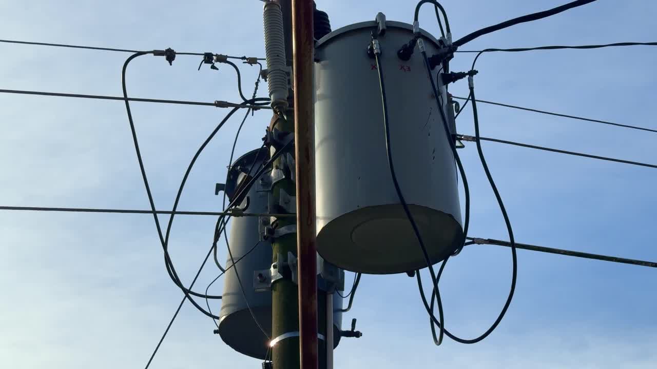 High-voltage transformers and electric cables on a power pole, illustrating rural or urban electrical utility systems