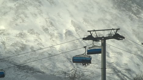 Ski-lift-carries-skiers-up-Tatranska-Lomnica-slopes,-High-Tatras-in-background