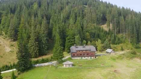 a drone shot of a wooden house in the countryside beside the forest