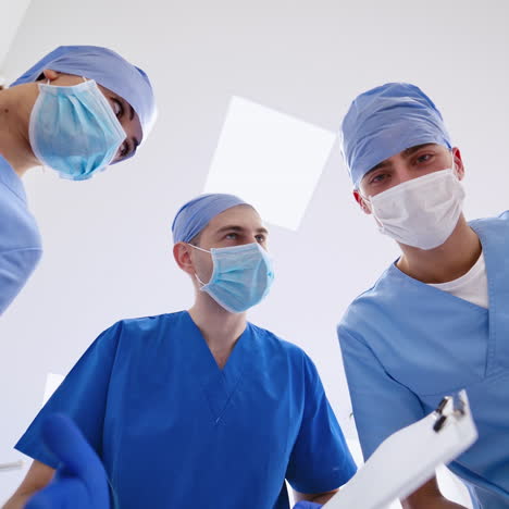 portrait of three doctors in masks. view from below on specialists in blue medical uniform in clinic. medical concept.