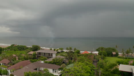 Dark-storm-clouds-on-a-tropical-beach-in-Canggu,-Bali-during-rain-season.-Aerial-view-of-beach-houses-before-the-storm-in-empty-tourist-resort