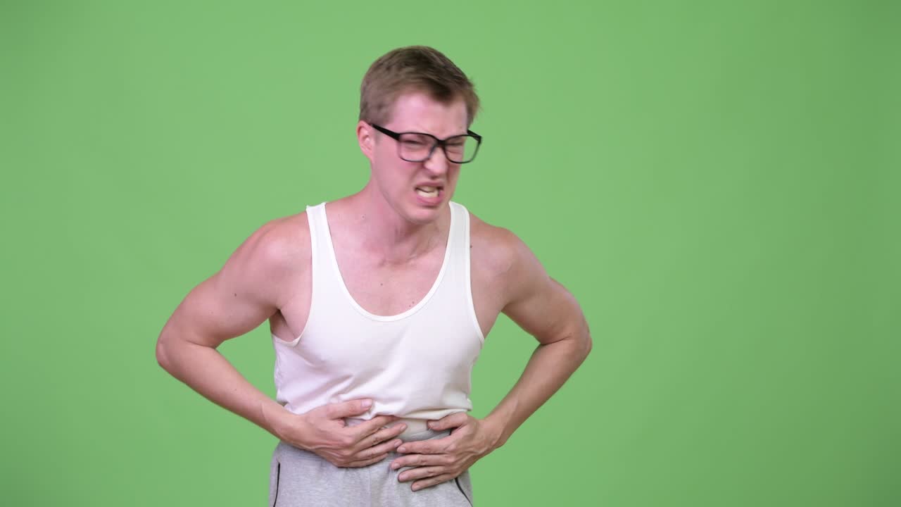 Young handsome nerd man having stomach ache