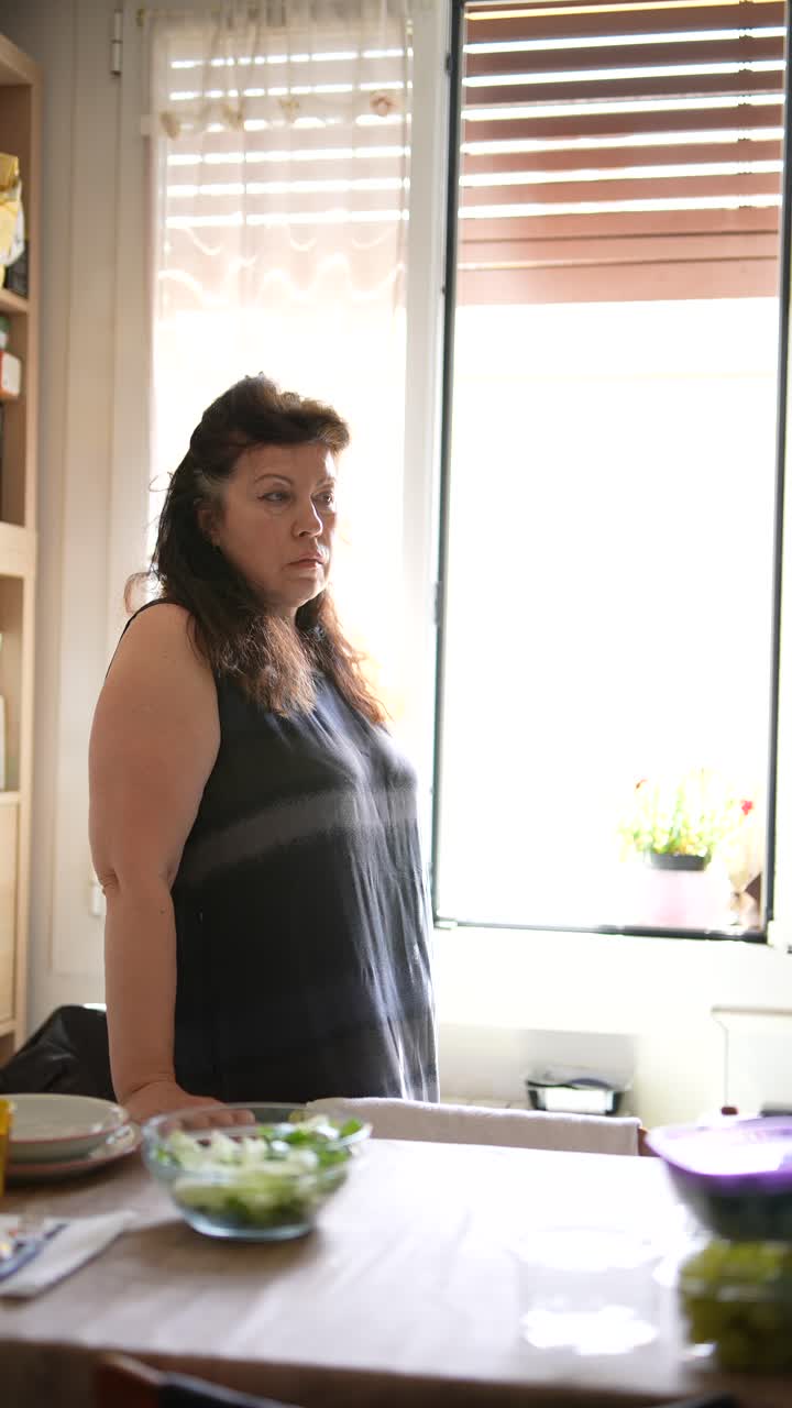 Donna che guarda fuori da una finestra della cucina
