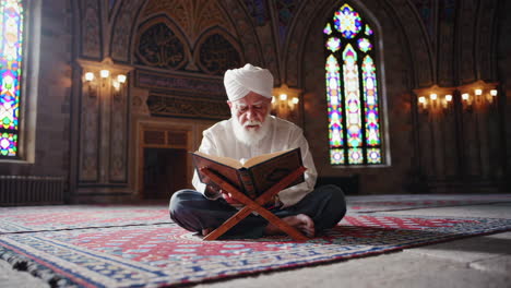elderly muslim man reading the quran in a mosque