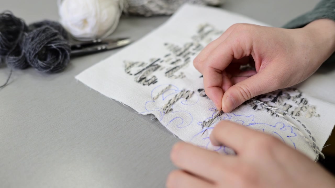 Close up of hands working with textile samples or fabric swatches on a design table, showing attention to detail in material selection and fabric composition