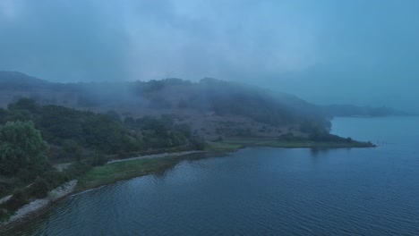 Misty-morning-over-Nanclares-de-Gamboa-lake,-Basque-Country,-Spain,-aerial-view