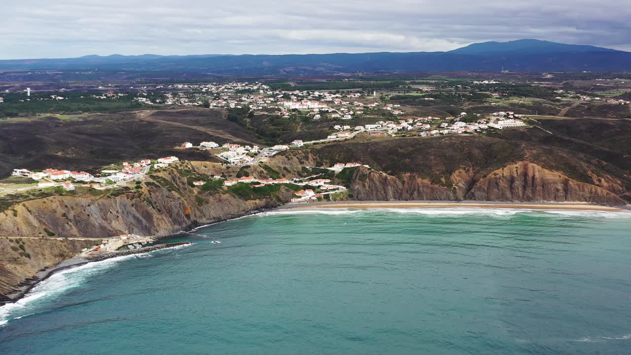 playa de praia da arrifana en el oeste de portugal con la ciudad de picao en la parte superior del terreno, toma panorámica aérea a la derecha