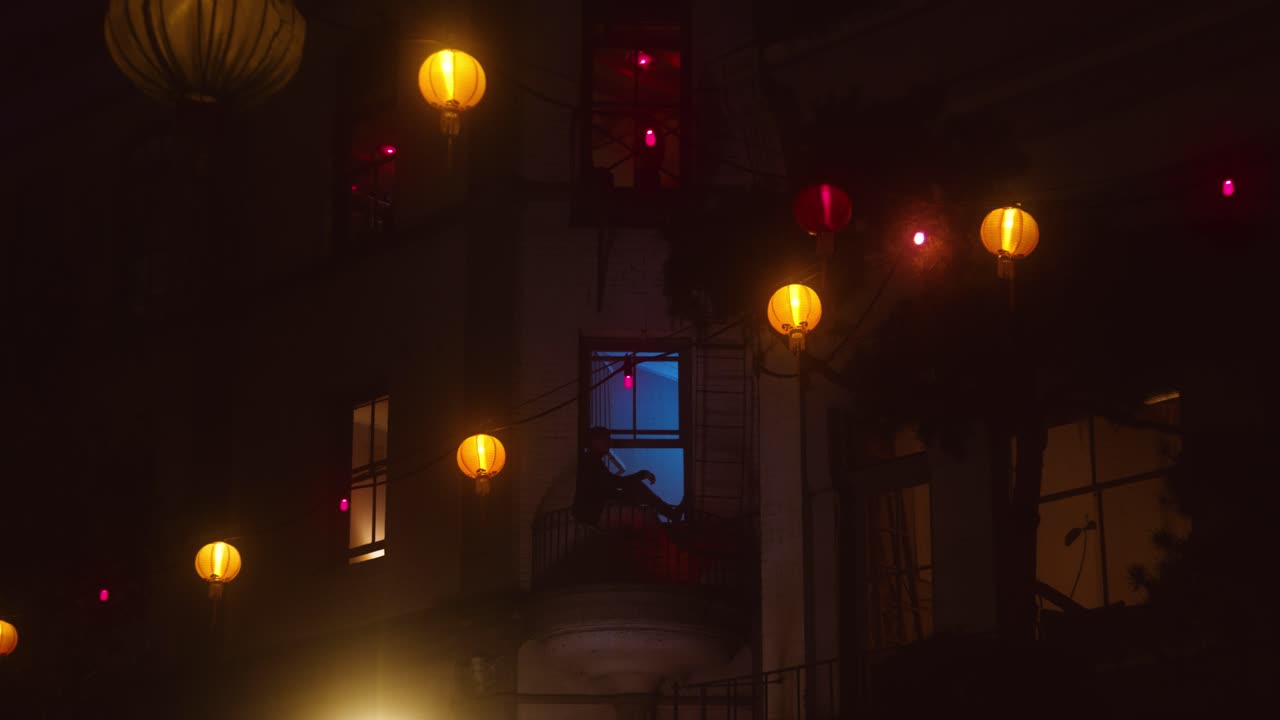 Man smokes in window frame downtown industrial district.