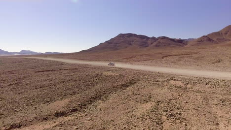aerial pan, car driving through rugged desert landscape in namibia, africa