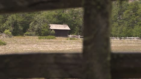 rack focus from wooden fence to horses barn in farm