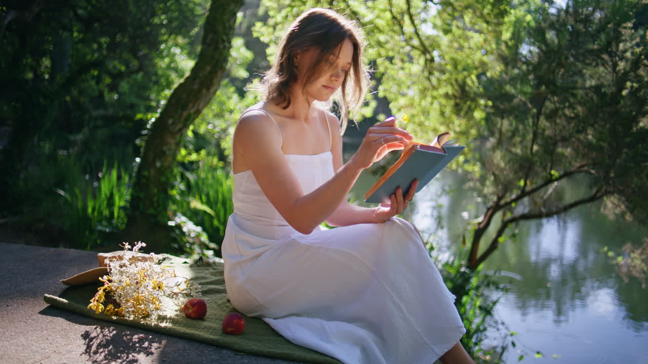 Intelligent woman enjoy book at nature near water. Pensive lady reading novel