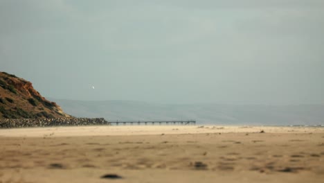 Windiger,-Nebliger-Strandozean-Mit-Steg-Und-Bergen-Im-Hintergrund-Am-Hafen-Noarlunga-In-Australien