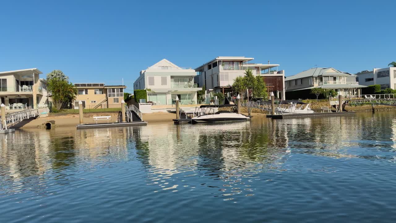 Ampia panoramica di ville moderne e barche che si riflettono nelle calme acque del canale sotto la luce del sole