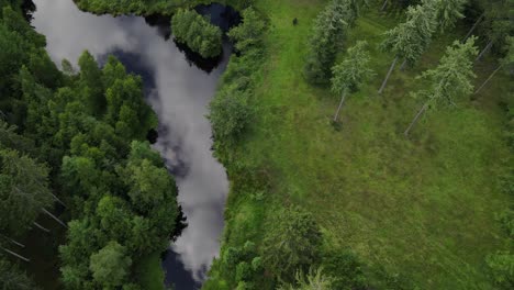 Aerial-footage-of-mirror-lake,-distant-people-and-a-forest