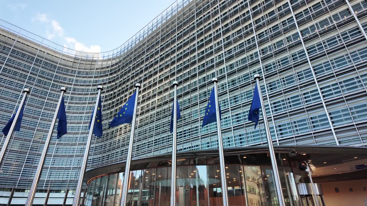 European Commission Berlaymont building with EU flags waving in Brussels