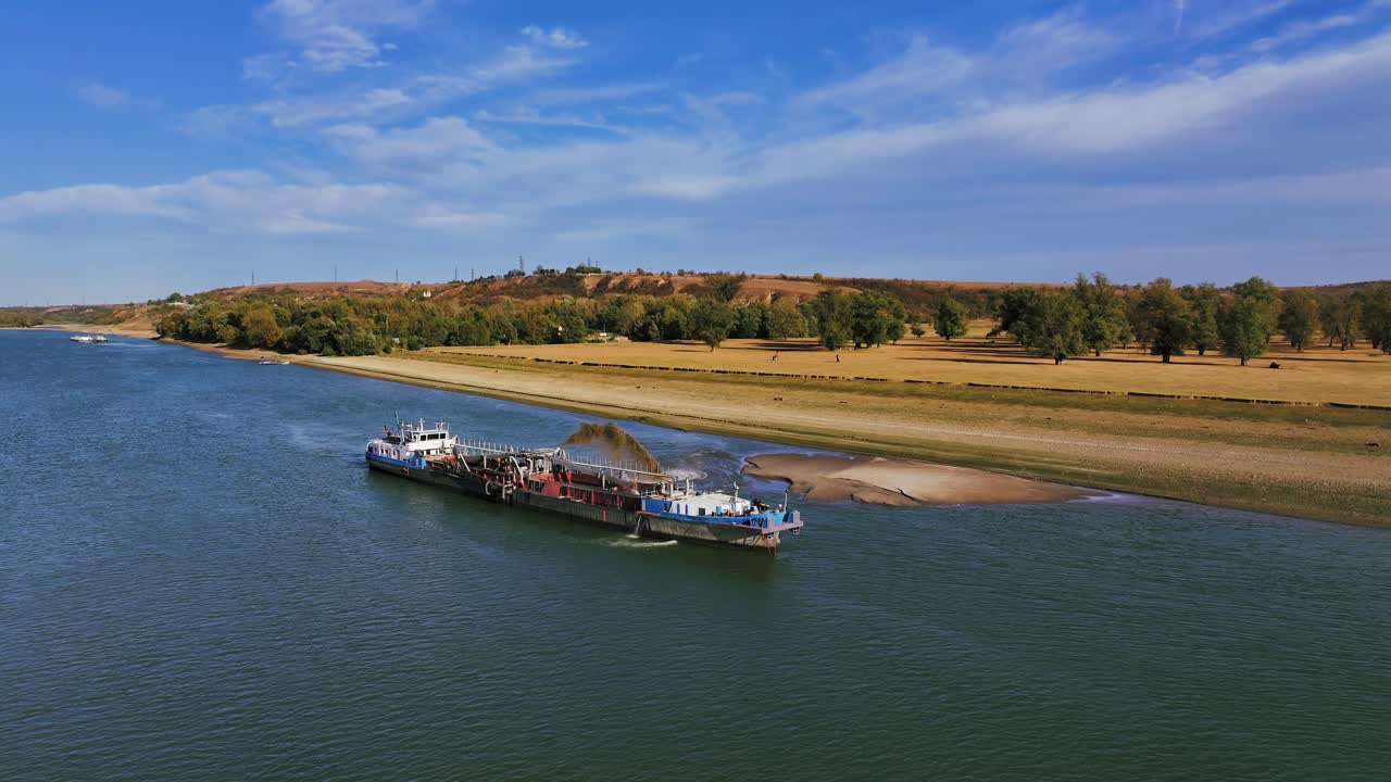 Aerial wide shot of a dredger unloading dredged sand on a big river, sunny day