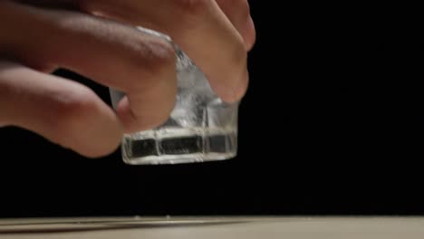 hand picking alcohol with ice on shot glass