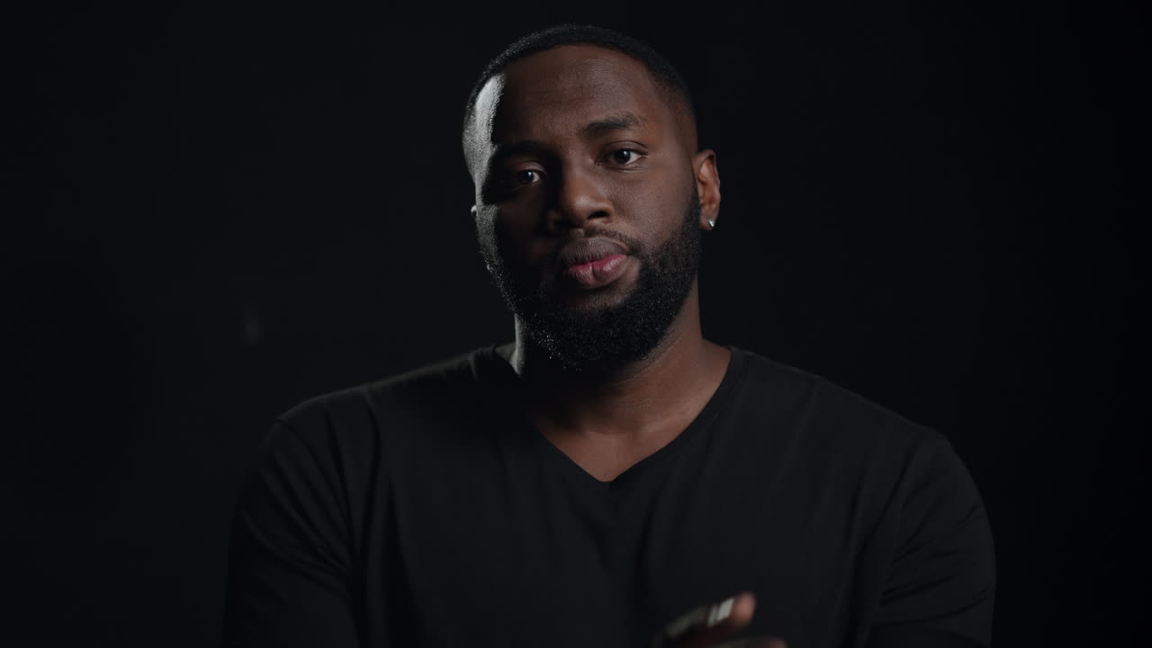 строгий афро парень смотрит в камеру в помещении. серьезный африканский мужчина скрещивает руки