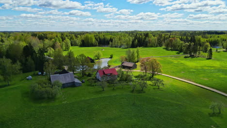 beautiful small farmhouse with vast green meadow and forest in latvia, aerial