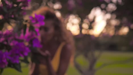 young woman alone in the park sniffing the scent of purple centradenia flowers - close-up shot