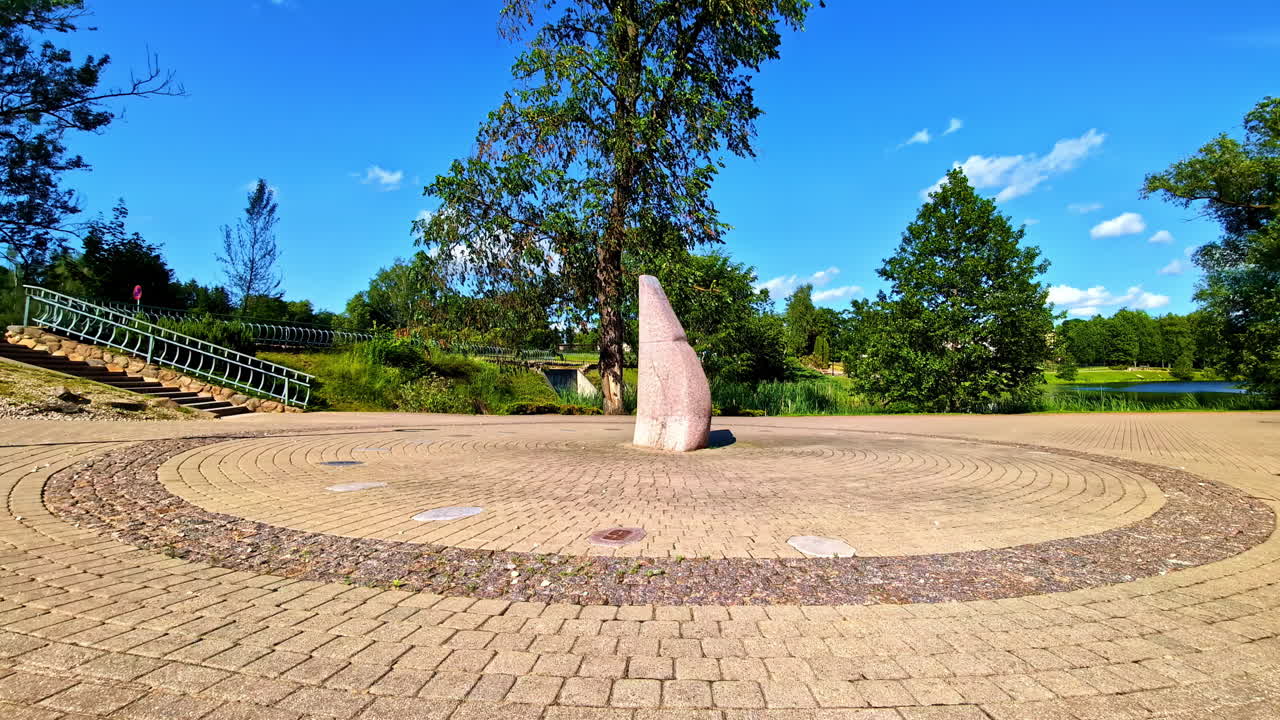 Large stone sun clock in circular pavement of public park under clear blue sky