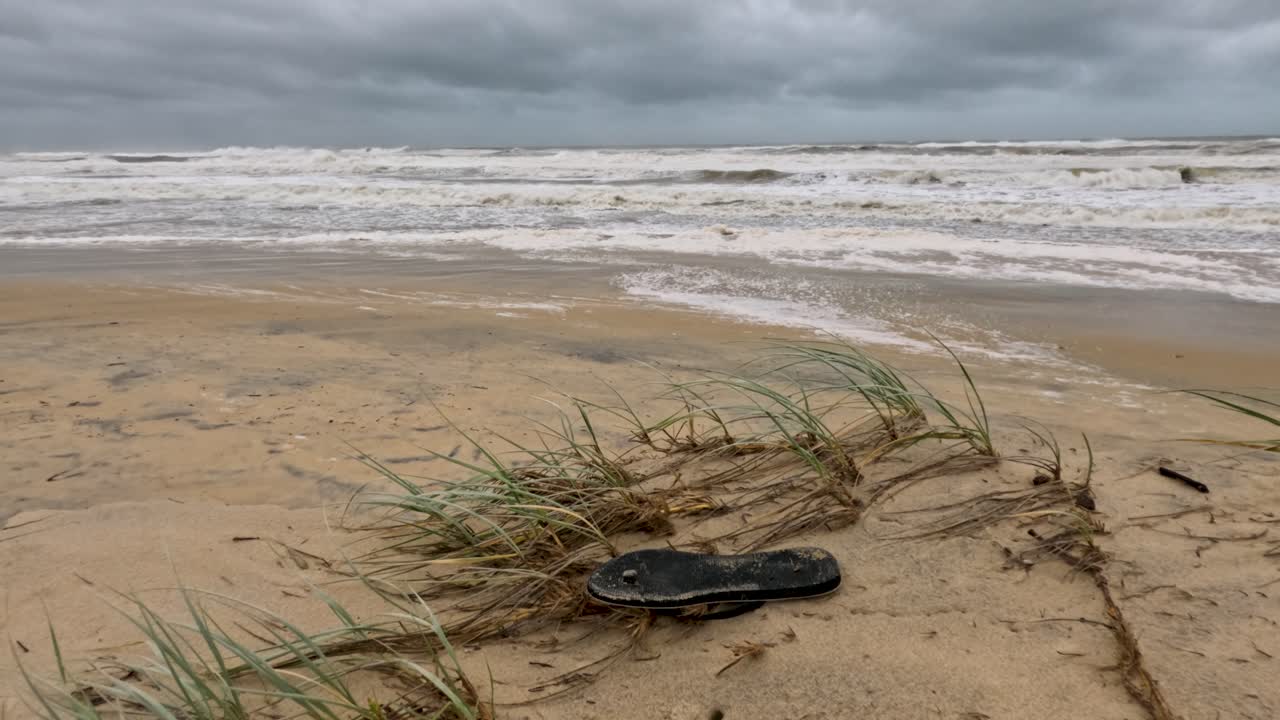бурная пляжная сцена с мусором и эрозией, подчеркивающая воздействие на окружающую среду и турбулентные погодные условия