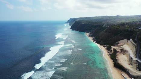 Wellen-Waschen-Sich-Am-Weißen-Sandstrand-Auf-Der-Paradiesischen-Insel-Mit-Steinbruch-Und-Wunderschönen-Klippen,-Bewölkter-Himmel