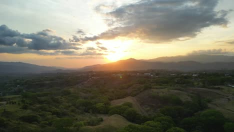 drone shot pulling away from beautiful sunset over mountains on the horizon