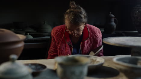 elderly woman working with wet clay in workshop. lady doing handcraft in studio.