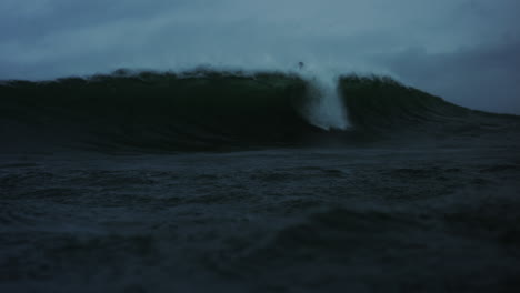 el surfista rompe a través de la parte superior de la ola cuando el labio se estrella en la superficie del agua, vista hacia abajo en el barril