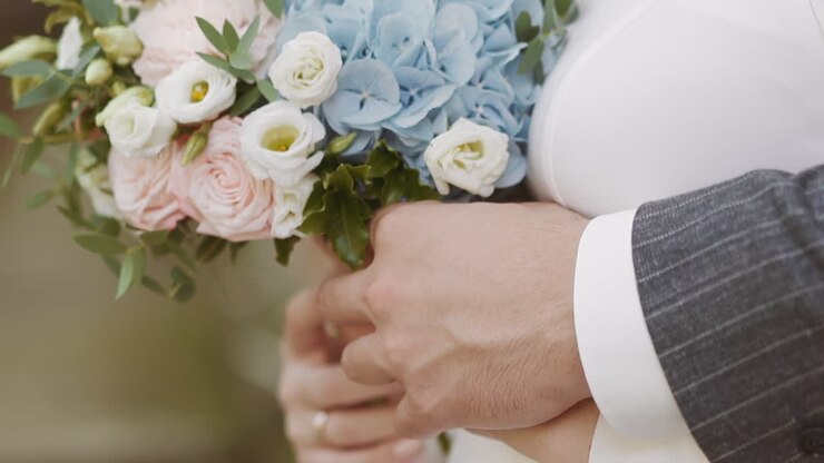 Careful man in jacket embraces wife holding gentle bouquet