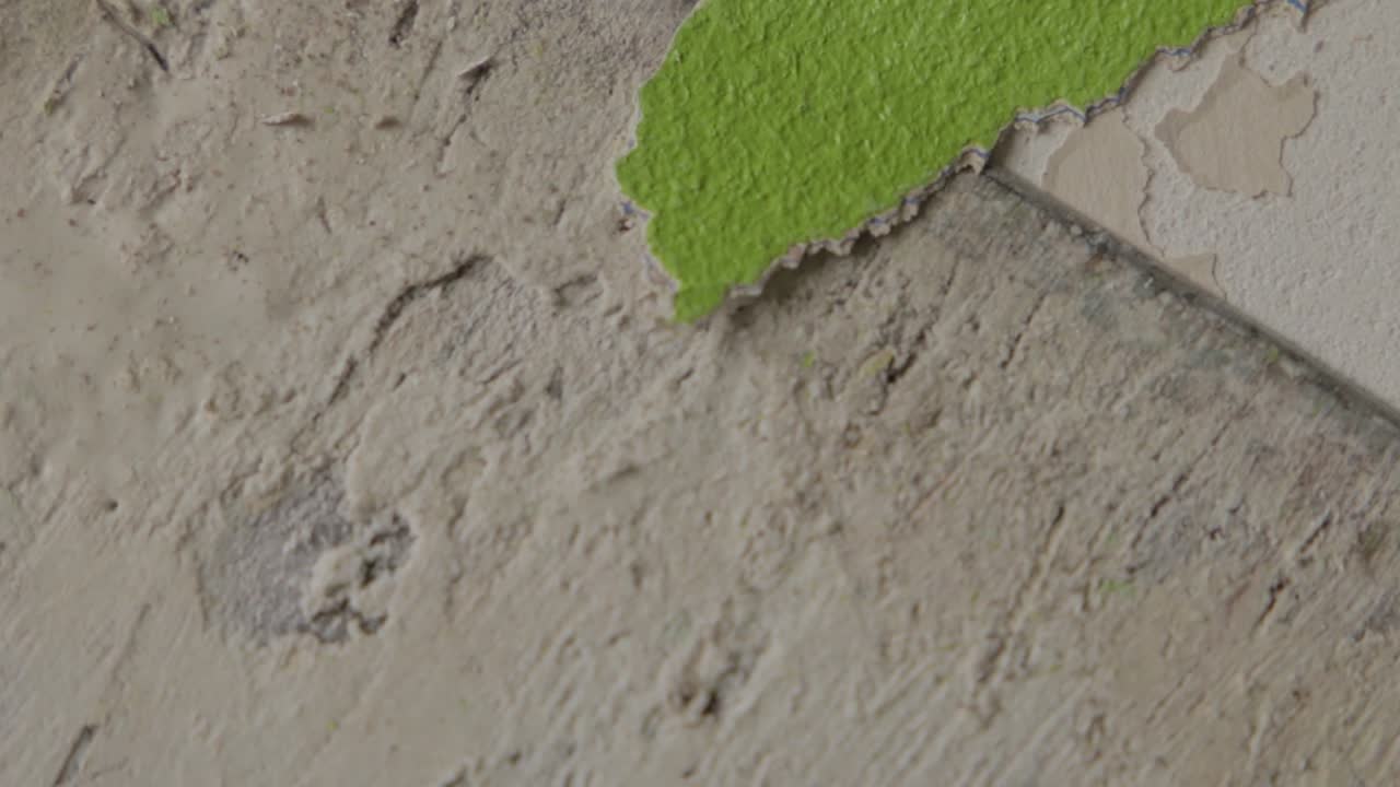 primer plano constante de un hombre raspando pintura verde de una pared durante las renovaciones.
