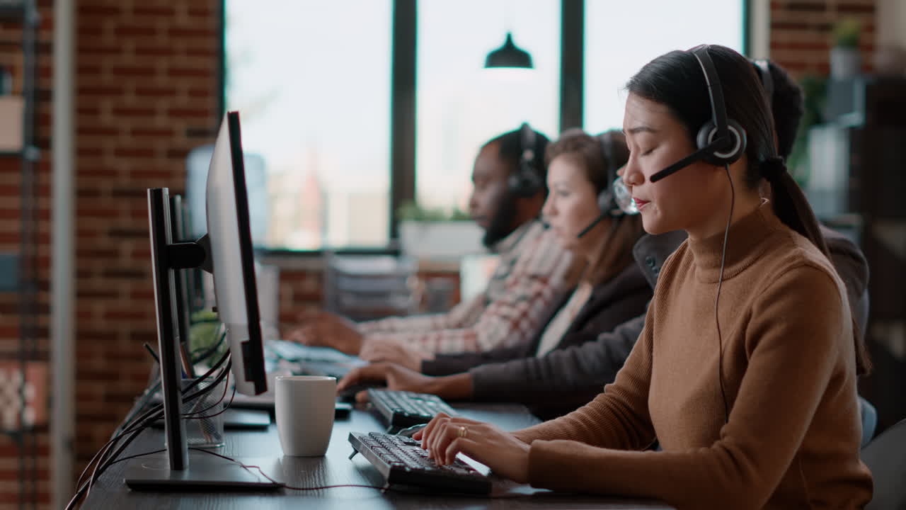 Asian woman using audio headset to have conversation at call center