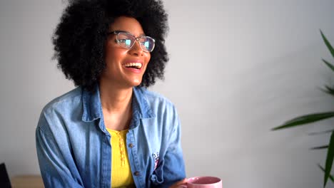 laughing black female using smartphone and drinking cup of coffee
