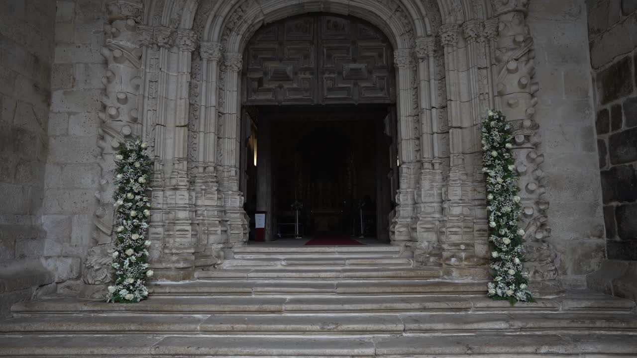 Grand stone church entrance adorned with tall floral arrangements on each side of the stairs