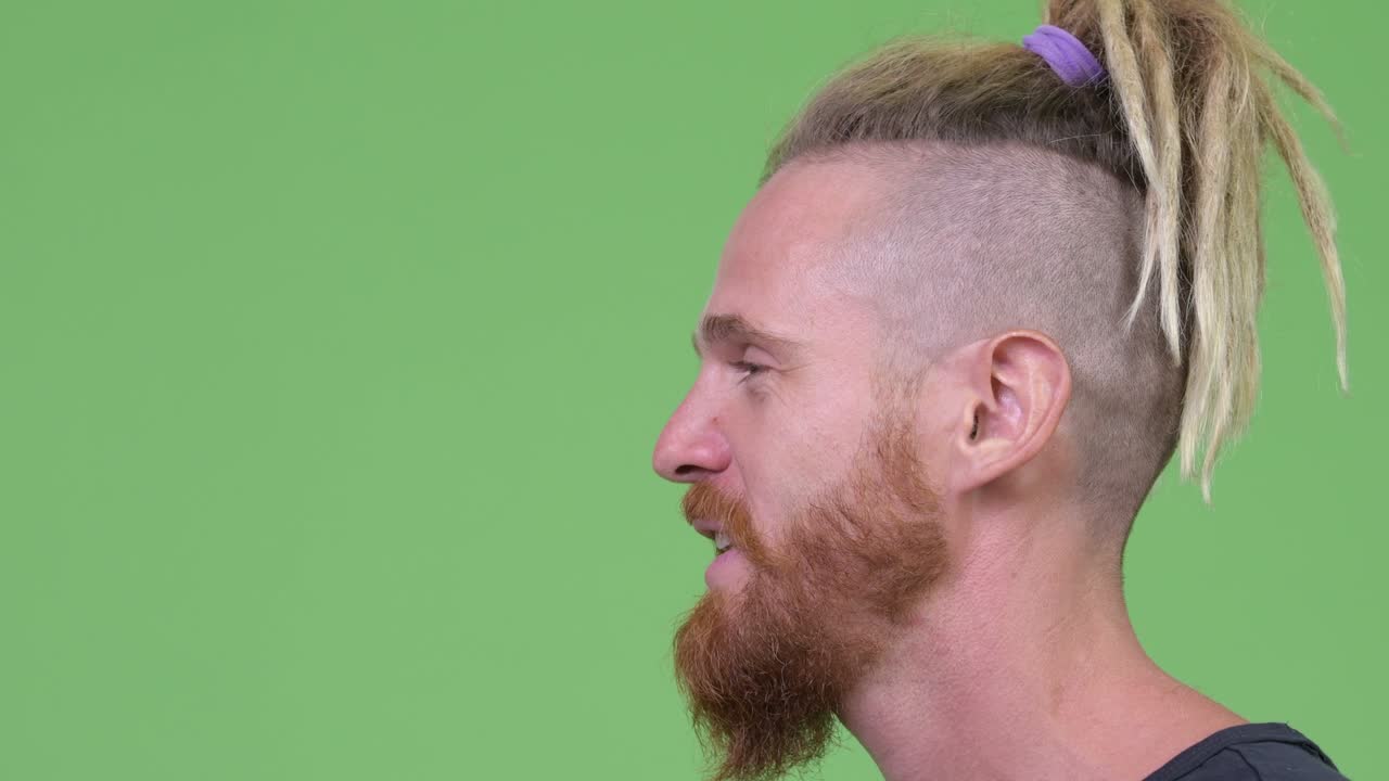 vista de perfil de un hombre barbudo con dreadlocks hablando