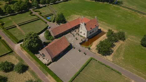 Parallax-aerial-shot-of-the-Castle-farm-De-Grote-Hegge-in-Thorn,-Maasgouw-in-the-province-of-Limburg-with-view-of-the-building-with-Dutch-architecture-and-beautiful-surrounding-landscape