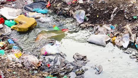 Corriente-Que-Fluye-Entre-Montones-De-Residuos-Plásticos-Y-Contaminación.