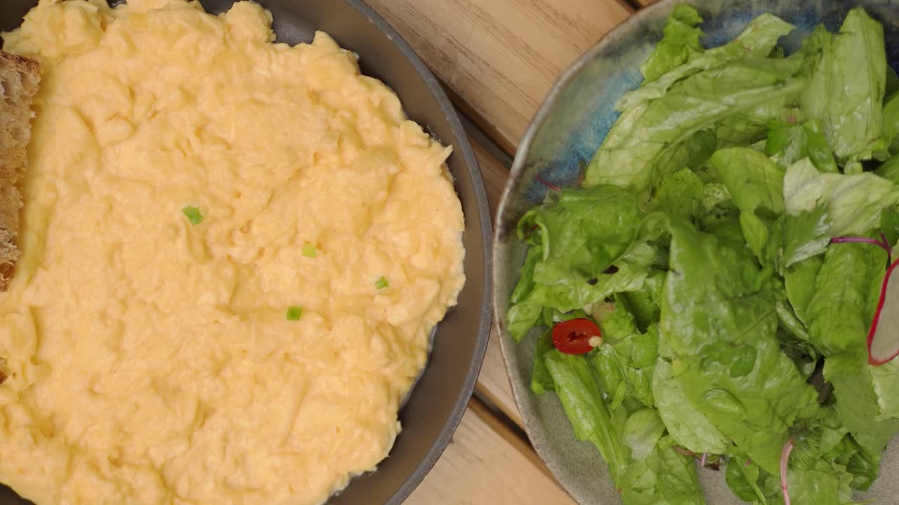 Scrambled Eggs with Toast and Fresh Salad on a Wooden Table