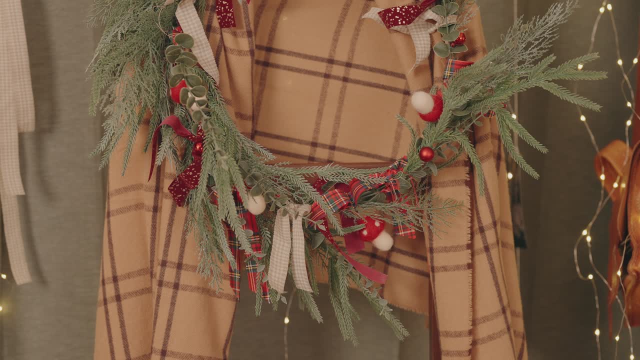 Festlig krans av städsegröna band och ornament hängde på en bakgrund av rutigt tyg