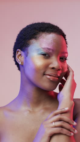 vertical video of african american woman with short dark hair in blue and pink light, slow motion