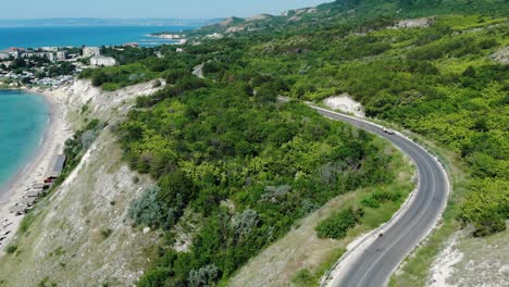 conducción de vehículos en la carretera costera en la colina en la costa de la playa de los héroes en balchik, bulgaria con vista panorámica del mar negro en el fondo