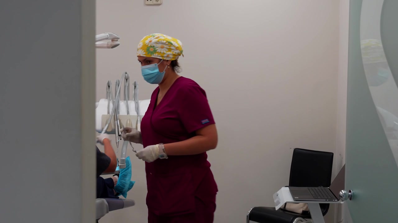 Igienista dentale che organizza gli strumenti dopo un trattamento in una clinica moderna con il paziente sulla poltrona.